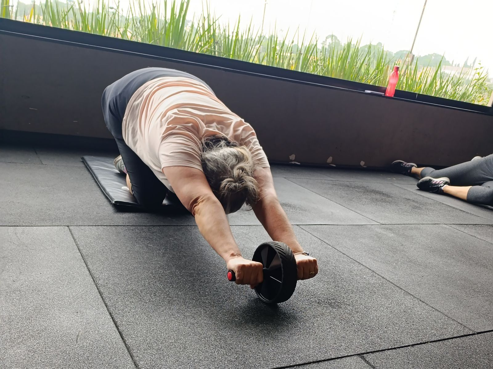 Aluna fazendo exercício abdominal com rolinho durante aula acompanhada