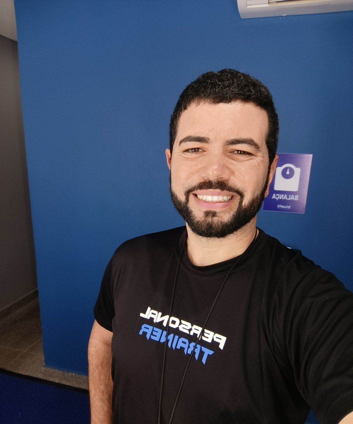 Luís Henrique Munhoz, o Personal Henrique, sorrindo com camiseta preta de personal trainer